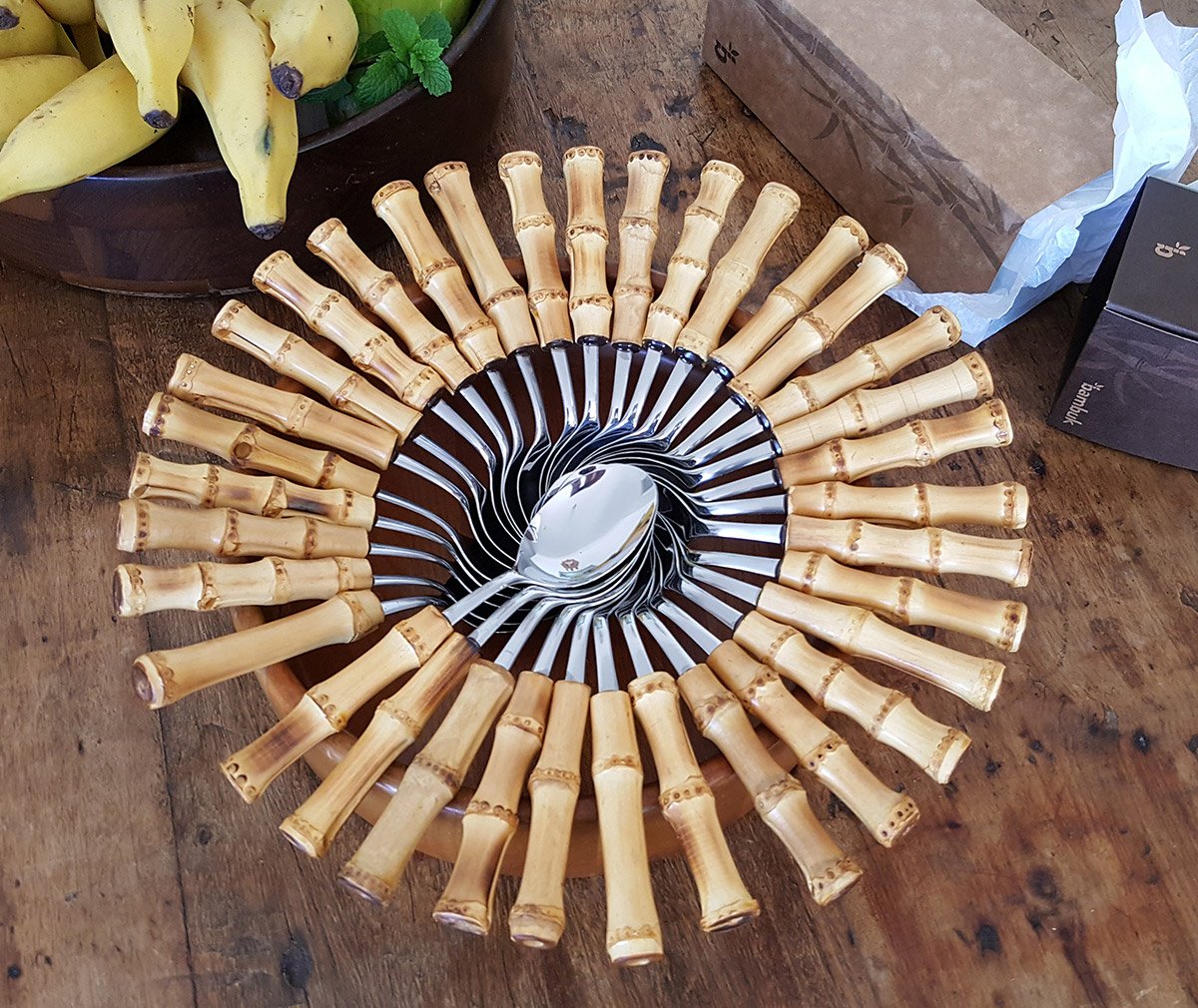 caracol-bambuk colhers de inox da tramontina com cabo de bambu natural colocadas em forma de caracol sob uma mesa elgante e rustica de madeira